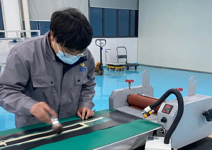 高(gāo)烯小(xiǎo)夥伴認真的(de)進行(xíng)覆膜工(gōng)作(zuò)